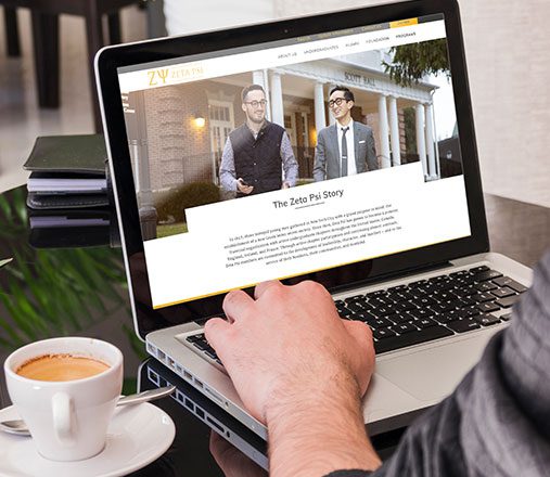 Man at computer viewing Zeta Psi Website Homepage