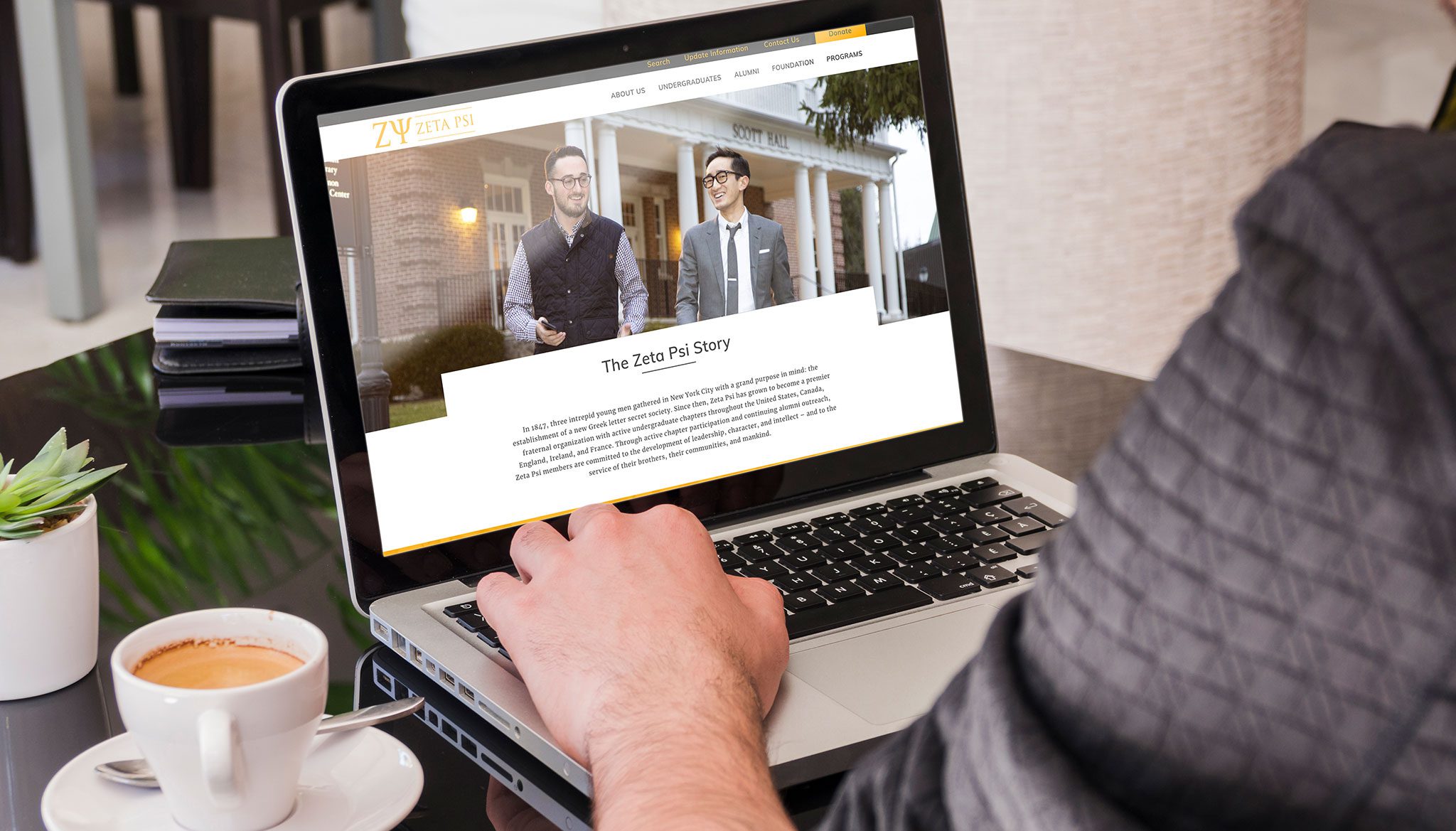 Man at computer viewing Zeta Psi Website Homepage