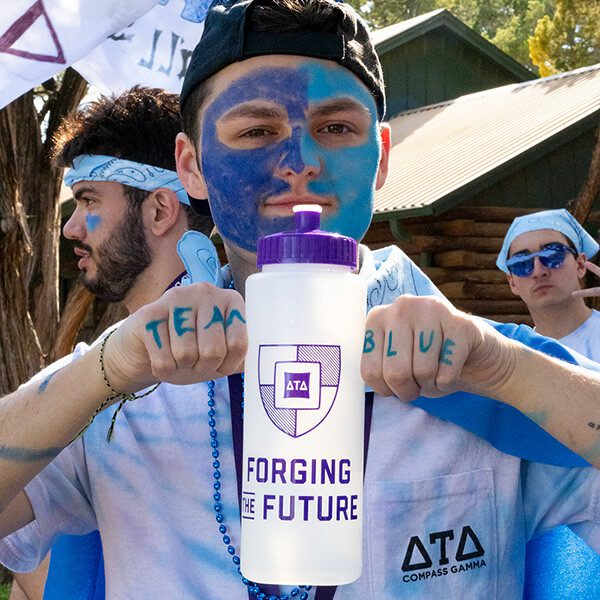 A boy with a painted face holds a white water bottle with the new Forging the Future logo on it