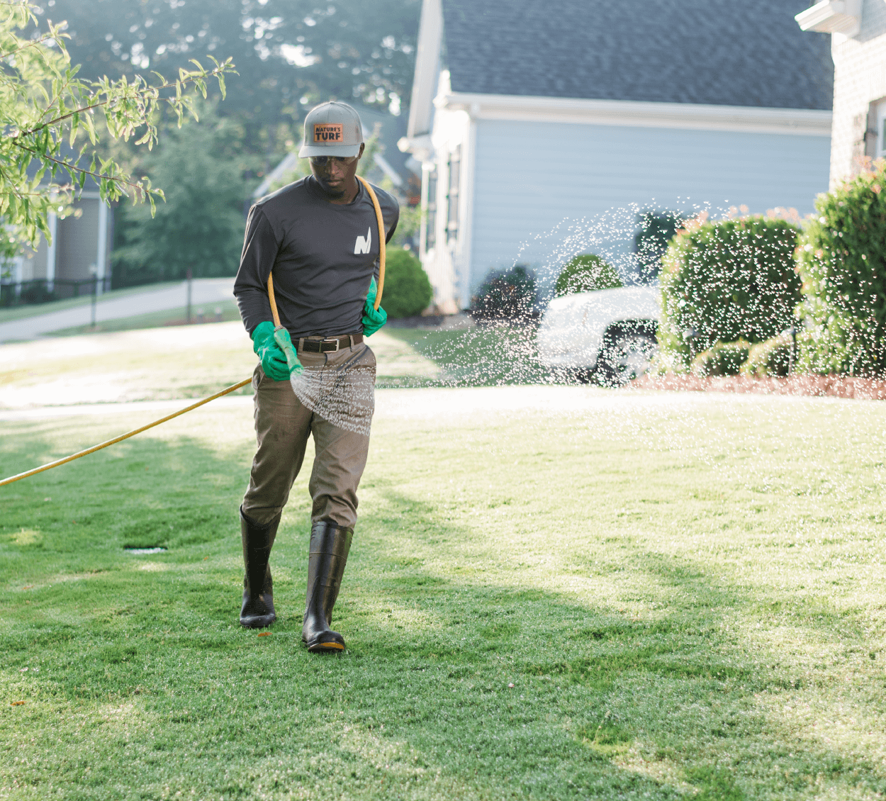 Photo of Nature's Turf team member watering a lawn