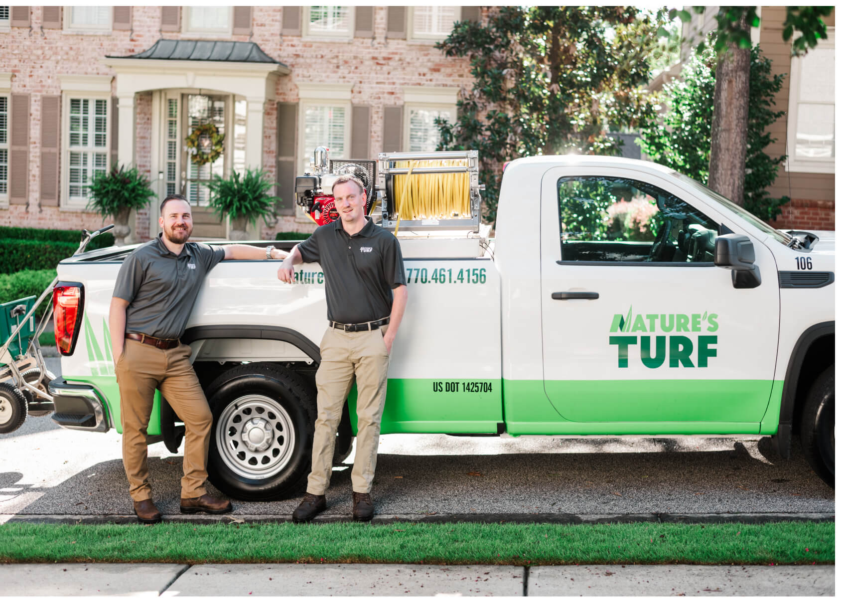 Two Nature's Turf staff members posing next to company truck