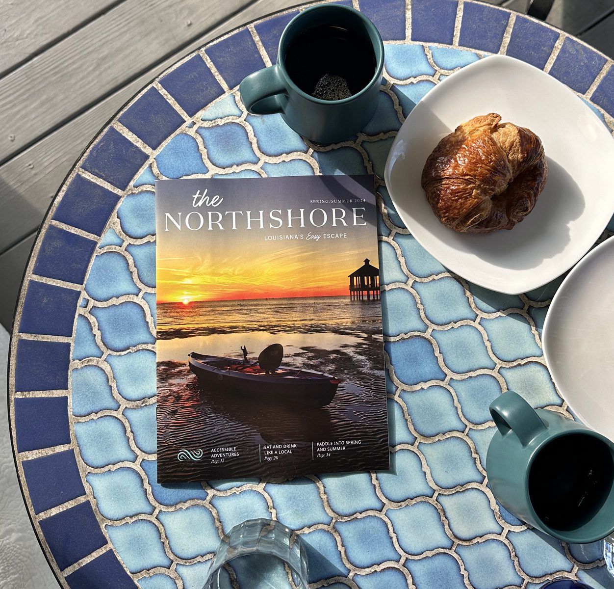 Visit The Northshore visitors guide sitting on a patio table surrounded by coffee and pastries